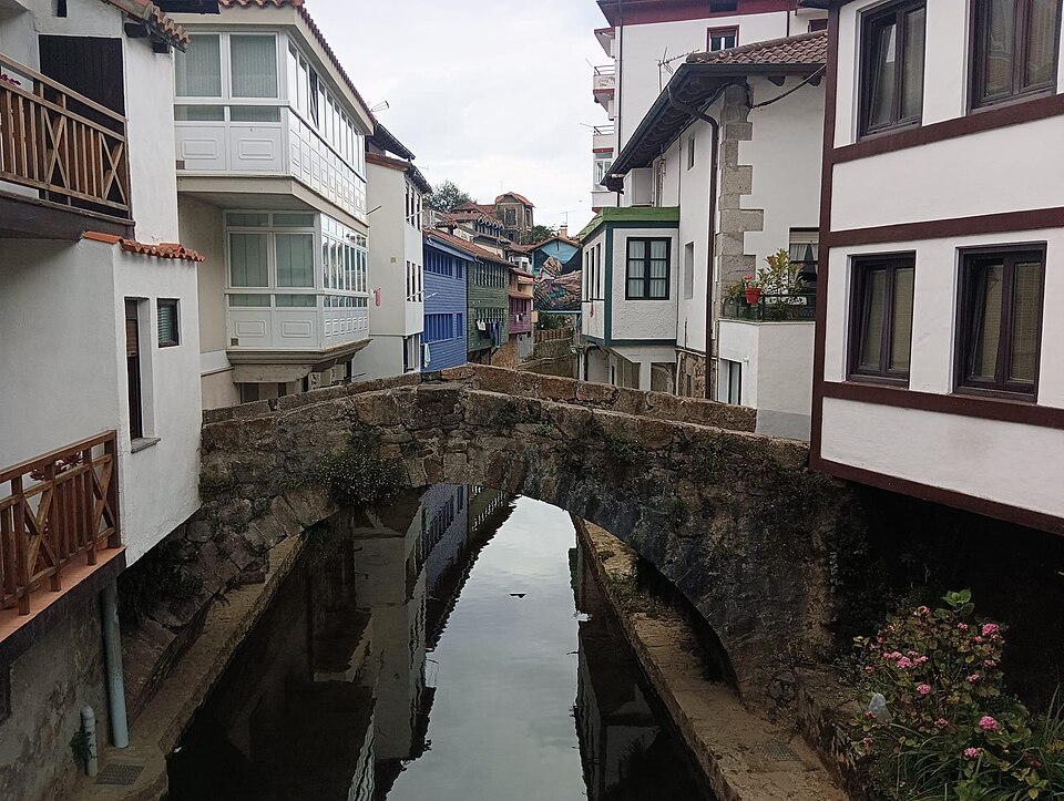 Puente medieval de piedra sobre la ría de Ea, con casas vascas de colores a ambos lados