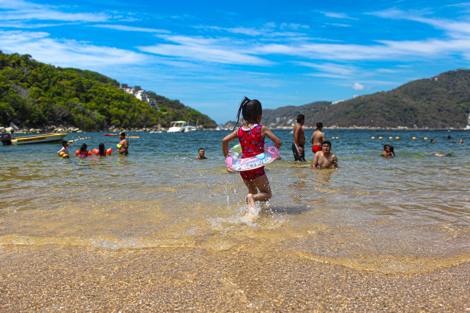 Playa tranquila de Acapulco con bañistas y colinas verdes