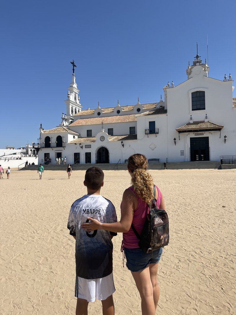 Ermita del Rocío vista desde la plaza de arena con visitantes paseando