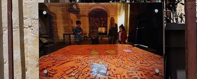 Familia con niños visitando la maqueta táctil de Monumenta Salmanticae en Salamanca